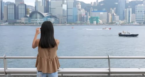 Woman taking photo on Victoria harbor in Hong Kong