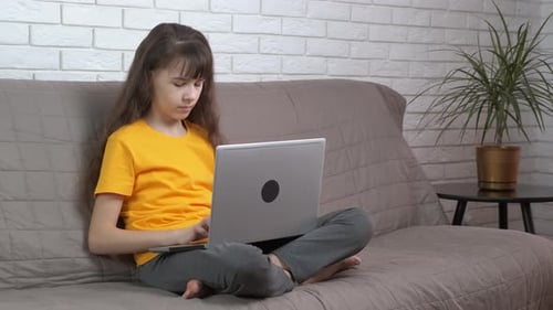 Girl Using Laptop While Sitting on Sofa