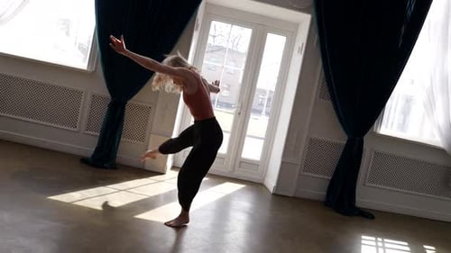 Young Blonde Woman is Dancing Contemporary Choreography in Light Hall Rehearsing Alone