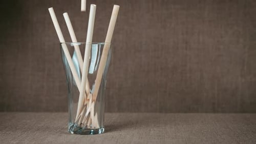 Paper Straws Falling into a Glass Cup