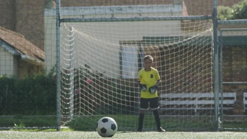 Afroamerikanisches Fußballkind in Rot, das an einem sonnigen Tag punktet
