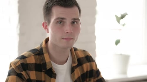 Young Adult Man Giving Thumbs Up Indoors