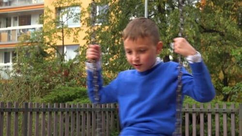 A Young Boy Plays with a Swing at a Playground