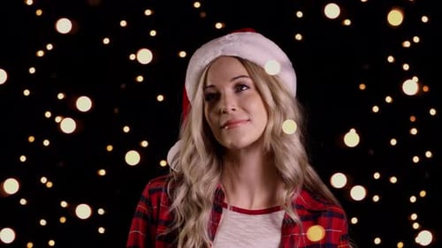 Woman Wearing Santa Hat Smiles Against Christmas Lights