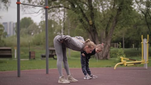 Mother and Daughter Doing Exercises on Open Air Sport Playground