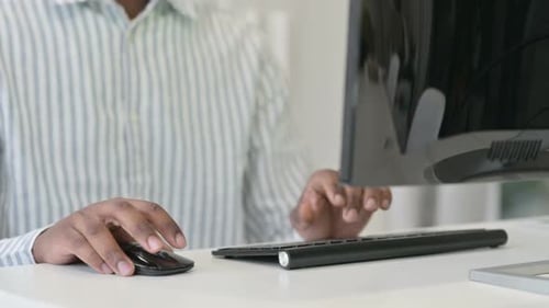 Close Up of African Man Using Mouse and Keyboard