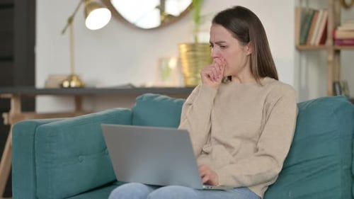 Woman Coughing While Working on Laptop at Home