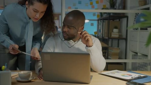 Gestresster Büroangestellter nutzt Laptop Dokumente von Kollegen, die sich nachts bei der Arbeit müde fühlen