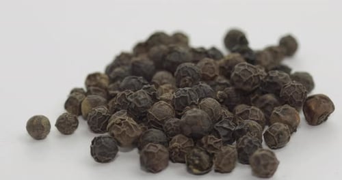 Heap of Black Peppercorns on White Background