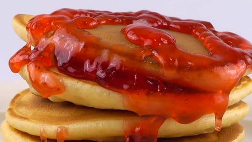 Strawberry Jam Being Poured on Stack of Pancakes