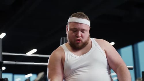 Overweight Man Eating Burger While Lifting Dumbbells