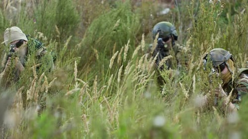 Bewaffnete Soldaten warten im Gras auf Feind