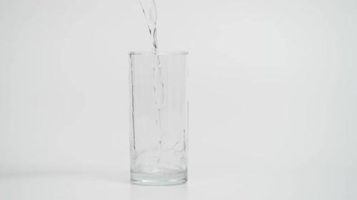 Water Pouring into Clear Glass on White Background