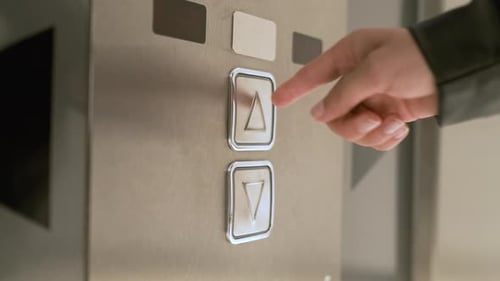 Frau drückt den Aufzugsknopf, um nach oben zu gehen