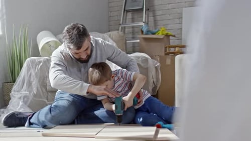 Father and Son Assembling Furniture Together Indoors