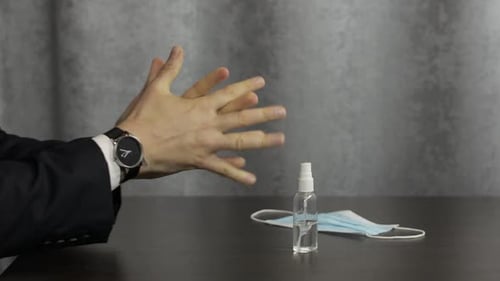 Man Applies Hand Sanitizer Near Surgical Mask