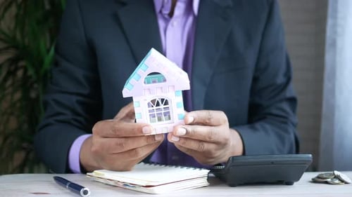 Business Person Holding Toy House in Office