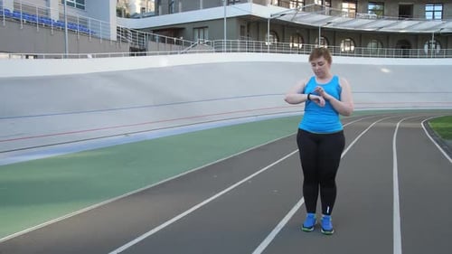 Woman Checking Smart Watch and Running on Track