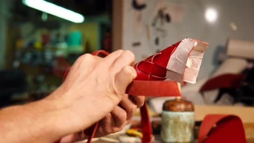 Hands Weaving Red Leather Strips Into Shape