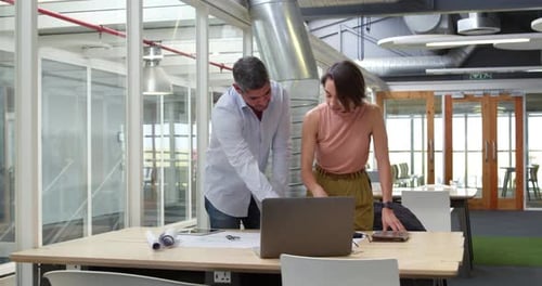 Business people discussing over blueprint in modern office