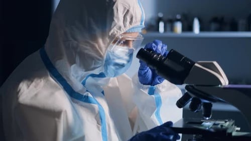 Scientist Examining Sample Through Microscope in Laboratory