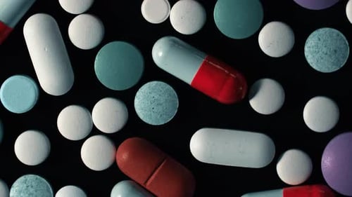 Pharmacy Theme. Multicolored Isolated Pills and Capsules Rotating on Black Surface. Vitamins, Drugs