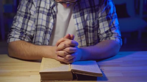Nahaufnahme Mann sitzt an einem Tisch und liest ein Gebet