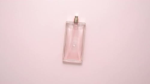 Vue de dessus d'une bouteille de parfum de luxe sur une surface rose pastel. Composition minimale. Lay plat