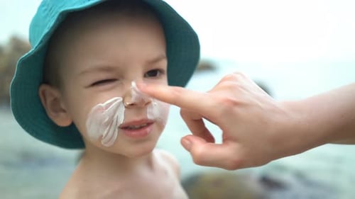 Mama maskiert ihren Sohn mit Sonnenschutzcreme