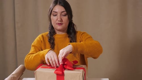 Woman Ties Ribbon on Holiday Gift