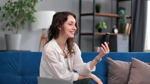 Woman Video Chats on Smartphone While Sitting on Couch