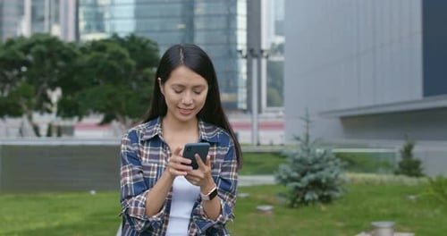 Woman Uses Smart Phone in City Park