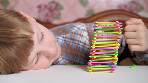 Niño construye una pirámide de palos de colores
