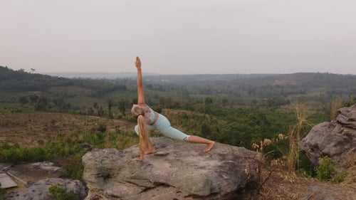 Aerial Shot of Lady in Downward Dog Yoga Pose with a View From the Top of the Mountain
