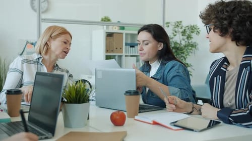 Slow Motion of Serious Women Discussing Project Looking at Papers and Talking in Modern Office