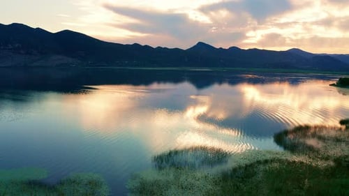 Rippled surface of a lake under beautiful colorful sunset sky, reflected in the water.