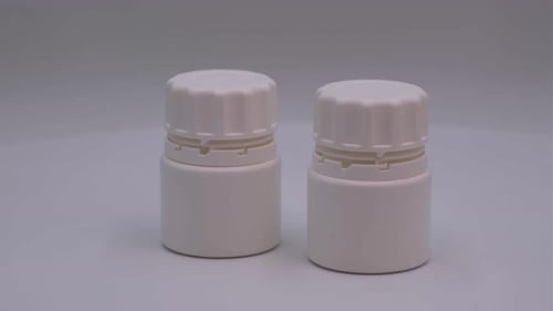 Two White Medicine Bottles on a Plain Background