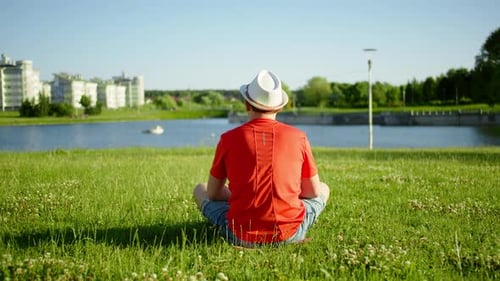A Man Sits on the Grass, Looks at the Pond, Camera Movement, Back View