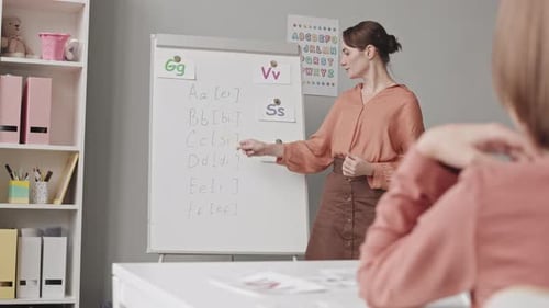 Teacher Explaining Alphabet to Young Student in Classroom
