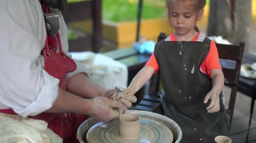 Girl Learning Pottery from Skilled Instructor Outdoors