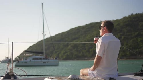 4K Portrait of Caucasian man drinking whiskey while travel catamaran boat sailing in the sea