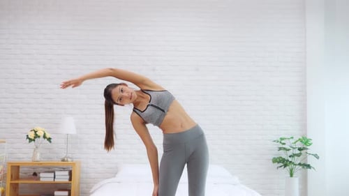 Woman Doing Side Stretches in Bedroom
