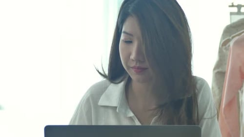 Woman Works on Laptop and Drinks Coffee Indoors