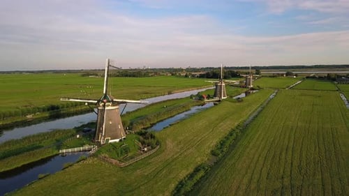 Countryside Scenery With Rustic Windmills On Meadow Landscape Against Blue Cloudy Sky In The Hague