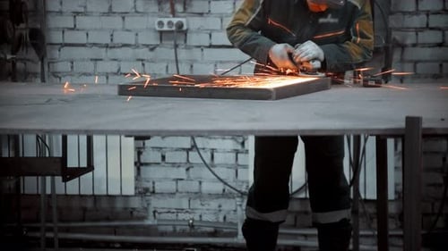 Man Worker Grinding the Seams of an Iron Frame in the Industrial Workshop