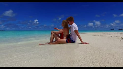 Two lovers tanning on exotic seashore beach trip by blue lagoon with white sandy background of the M
