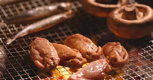 Barbecue mit Hühnerflügel, Champignons und Lodde auf gegrilltem Netz