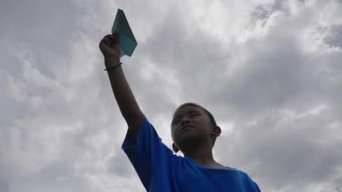 Boy Holding a Paper Airplane to the Sky