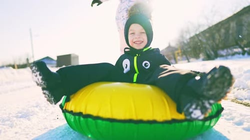 Excited Boy Sledding on Inflatable Snow Tube in Winter