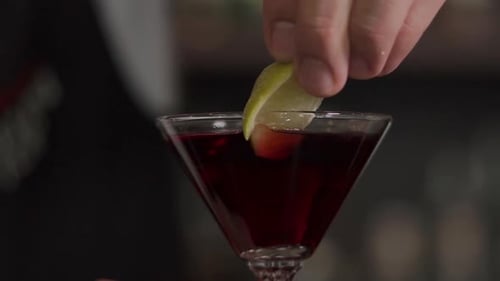 Nahaufnahme eines Glases mit einem alkoholischen Cocktail, in dem Limette lag